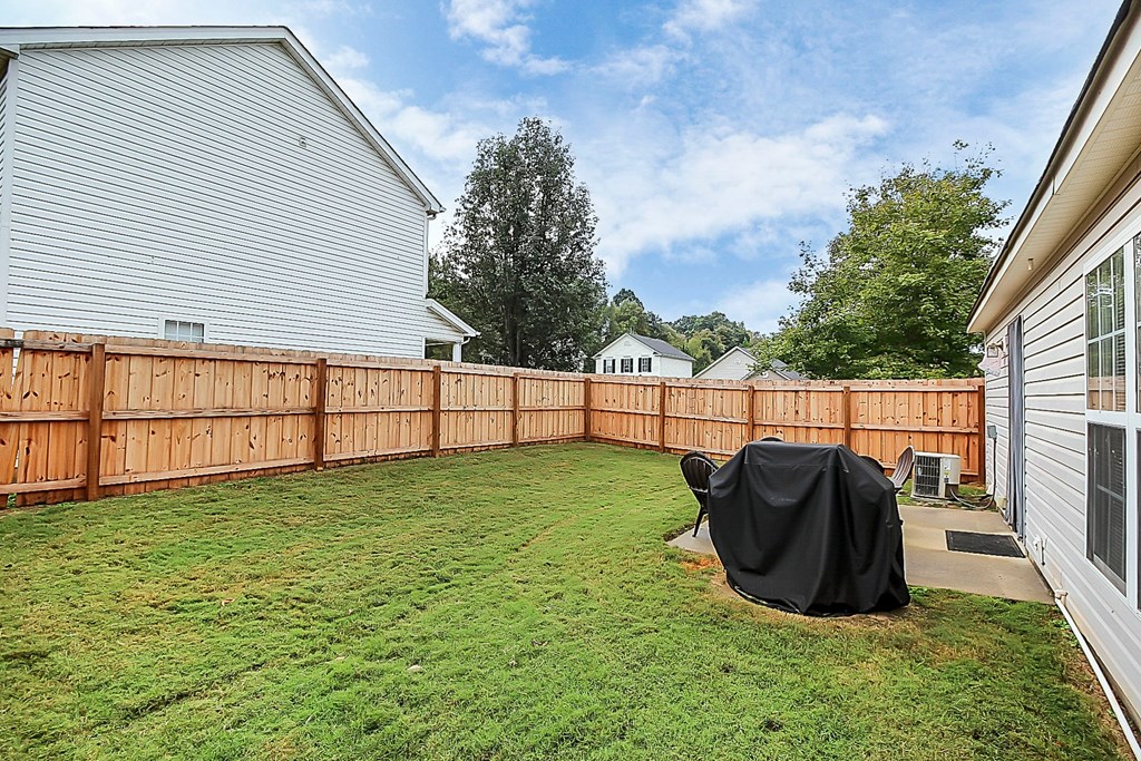 a backyard with a privacy fence and a yard with a covered chair