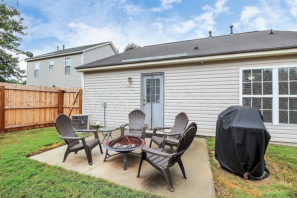 a backyard patio with a table and chairs and a fire pit