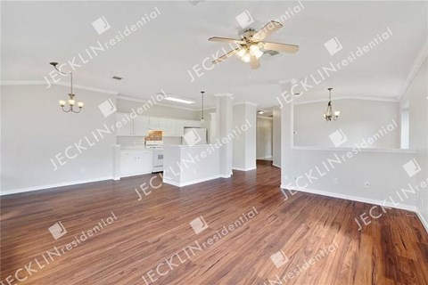 A spacious room with wooden floors and a ceiling fan.
