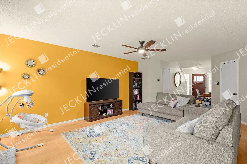 A living room with a grey couch and a television on a wooden stand.