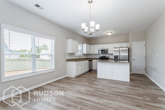 a large kitchen with white cabinets and a large window