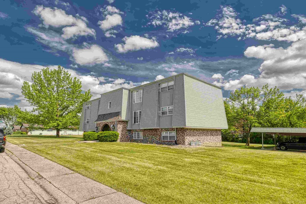 A modern house with a grey exterior and a green roof.
