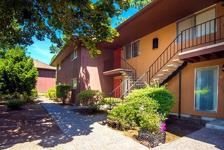 an apartment building with stairs and bushes in front of it