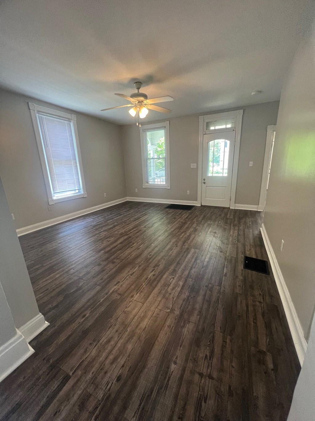 an empty living room with wooden floors and a ceiling fan