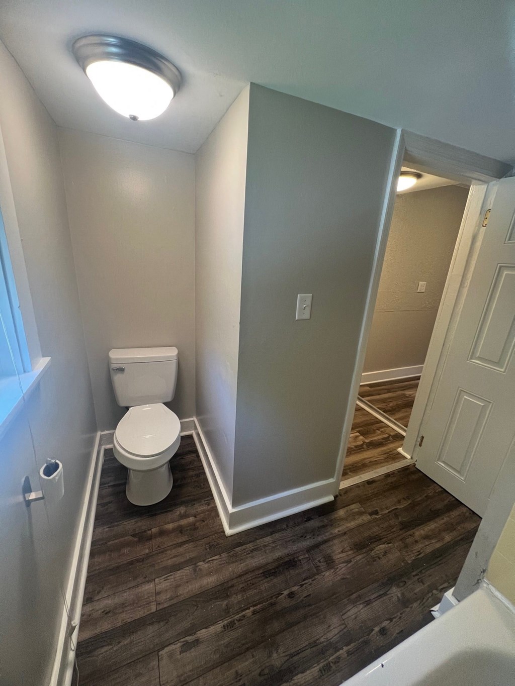 a small bathroom with wood flooring and a toilet