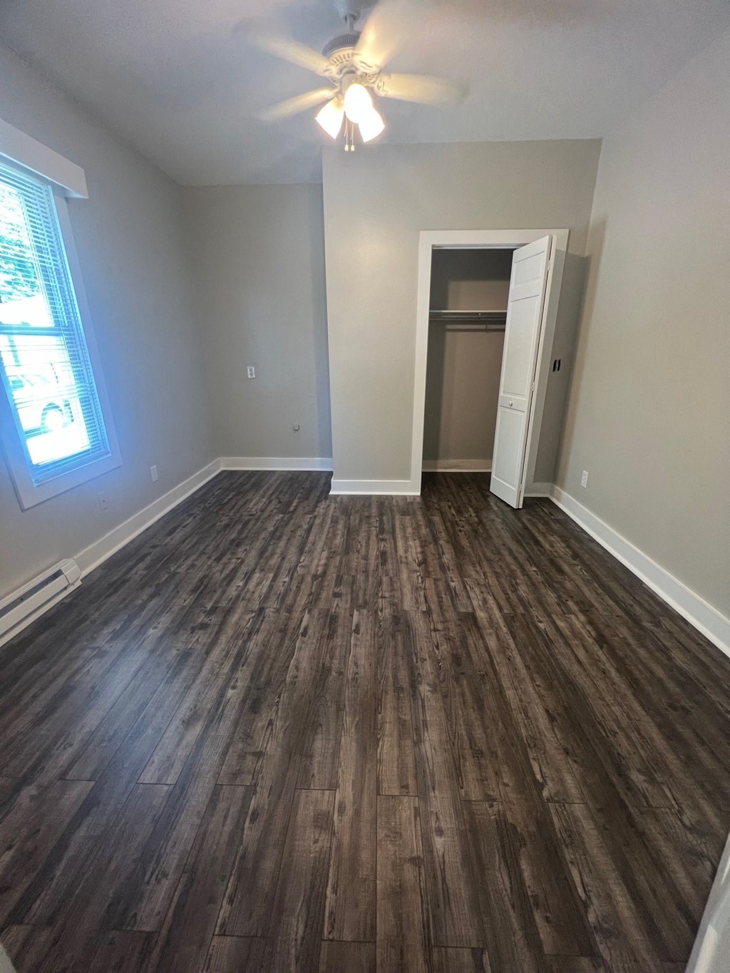an empty living room with wooden floors and a ceiling fan
