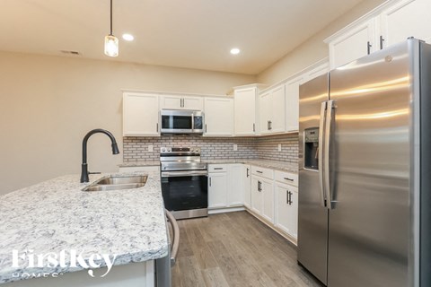 A kitchen with a stainless steel refrigerator and a granite countertop.