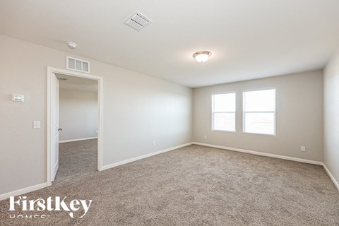 A spacious room with a carpeted floor and a window with blinds.