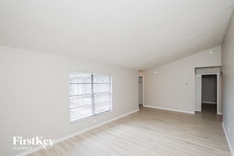 A spacious empty room with a window and a door in the background.