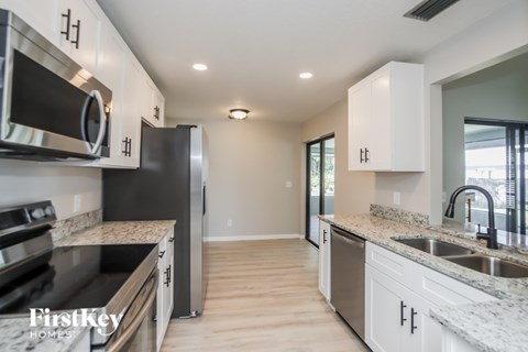A kitchen with a black refrigerator and stove top oven.