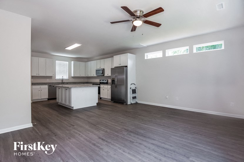 an empty living room and kitchen with a ceiling fan