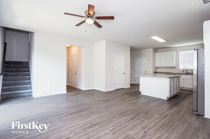 an empty living room and kitchen with a ceiling fan