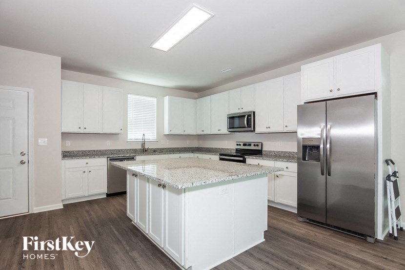 a large kitchen with white cabinets and stainless steel refrigerator