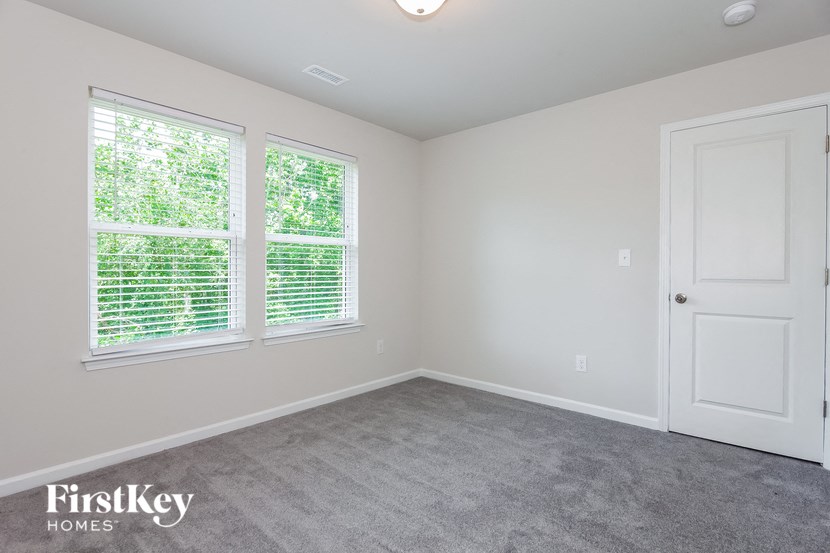 an empty bedroom with a door and two windows