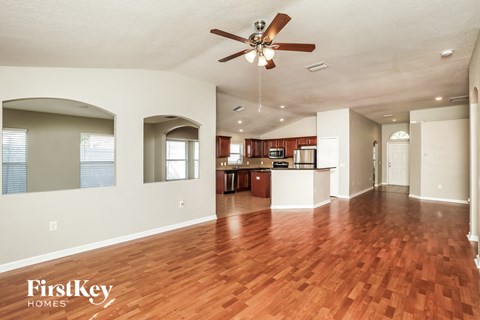 A spacious living room with a wood floor and a ceiling fan.
