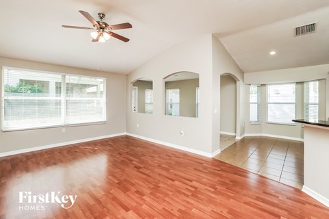 A spacious room with a ceiling fan and wooden flooring.