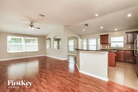 A spacious kitchen and living room with wood flooring and a ceiling fan.