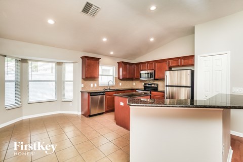 A kitchen with brown cabinets and a black counter top.