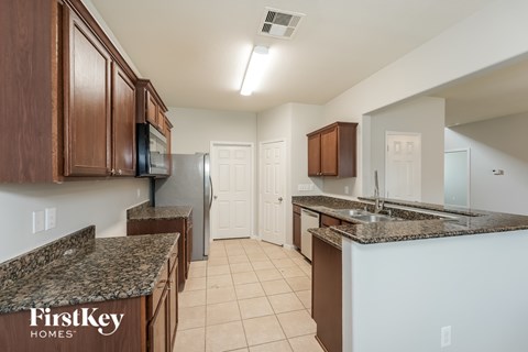 A kitchen with brown cabinets and a granite countertop.