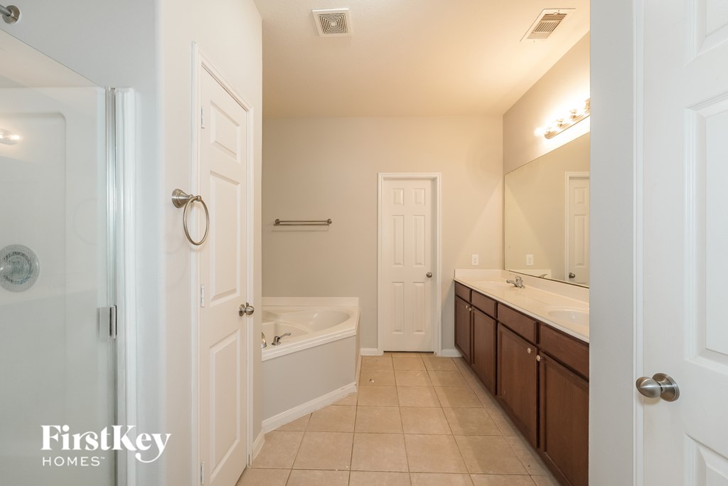 A white bathroom with a tub, sink and mirror.