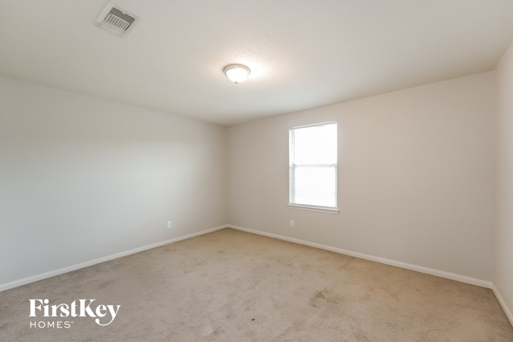 A room with a window and a carpeted floor.
