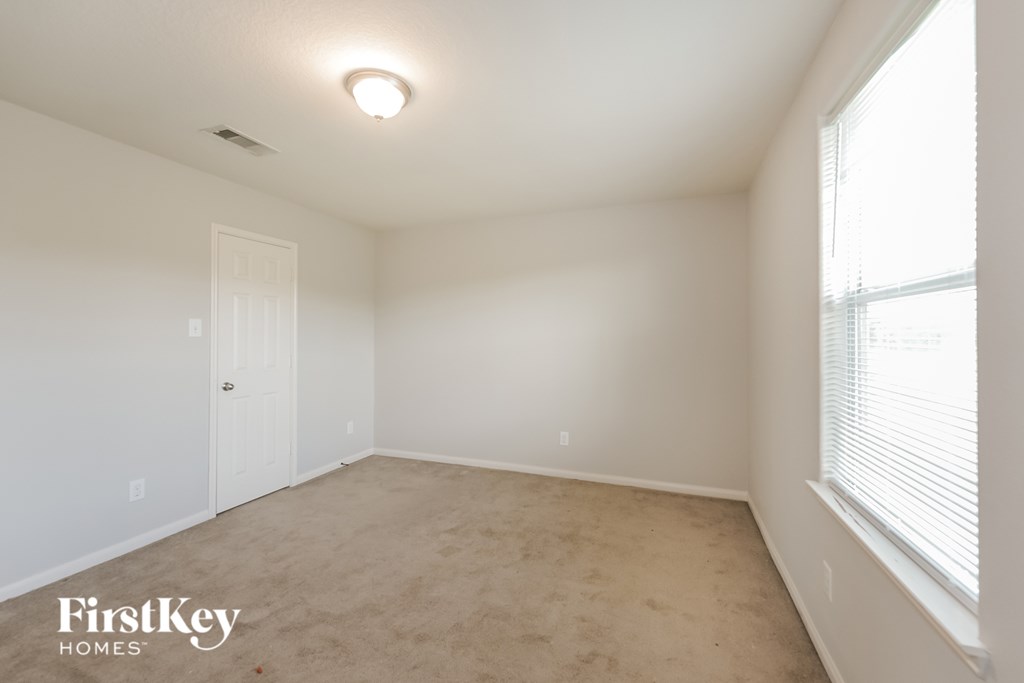 A room with a carpet floor and a window with blinds.