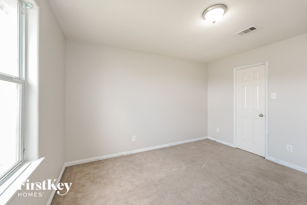 A room with a carpeted floor, a door, and a window.