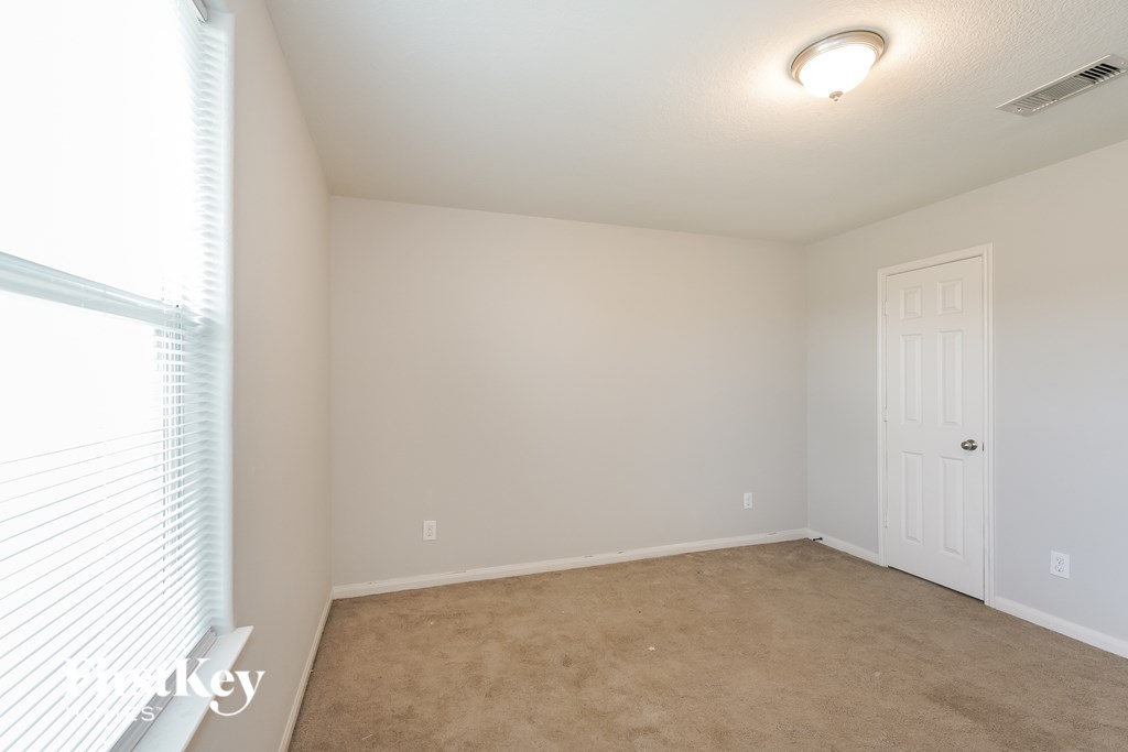 A room with a white door and carpeted floor.