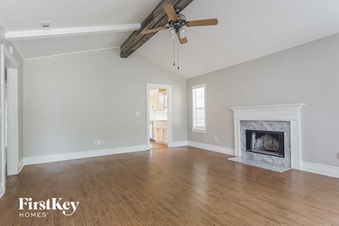 A spacious living room with a fireplace and a ceiling fan.