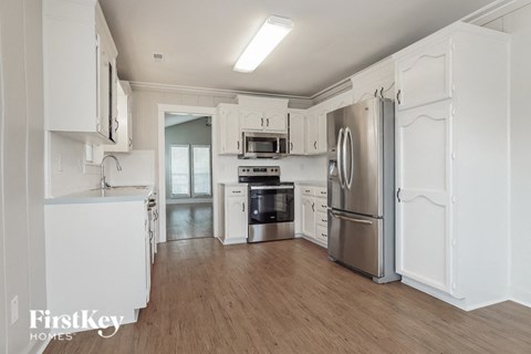 A kitchen with white cabinets and a stainless steel refrigerator.