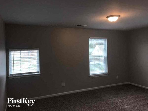 an empty room with two windows and a light on the ceiling