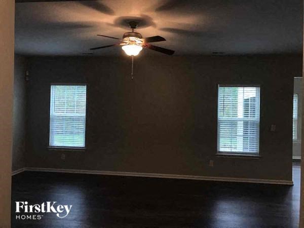 a living room with a ceiling fan and two windows