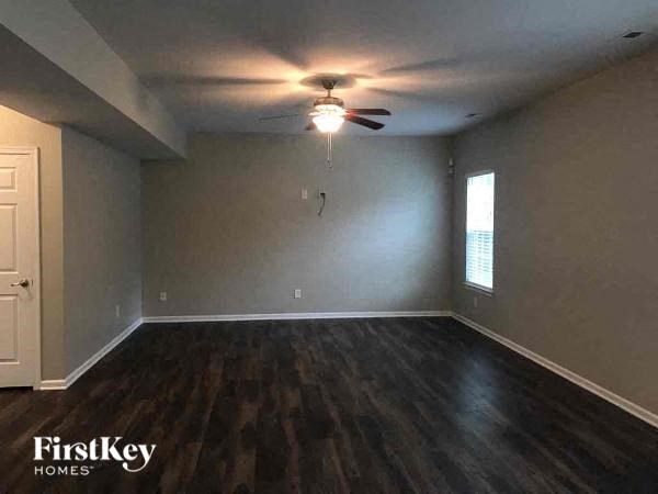 a empty living room with a ceiling fan and wood floors