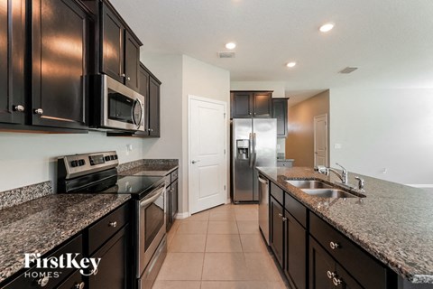 a kitchen with granite counter tops and black cabinets and stainless steel appliances
