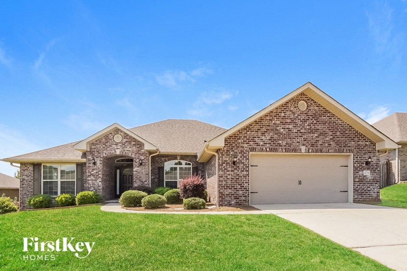 a brick house with a garage door and a lawn