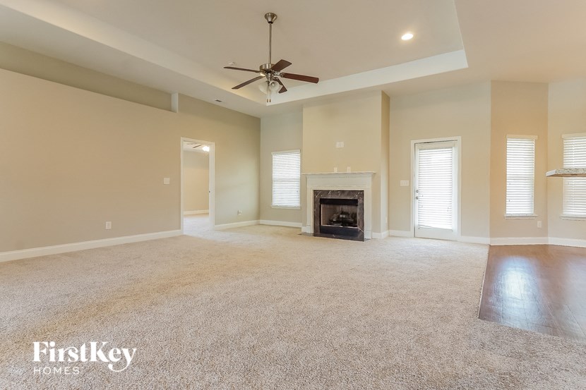 a empty living room with a fireplace and a ceiling fan