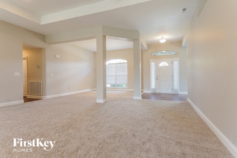 an empty living room with white pillars and a white door
