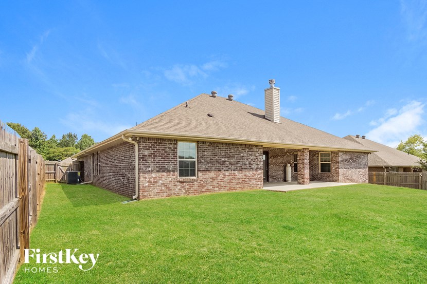 a brick house with a grassy yard and a wooden fence