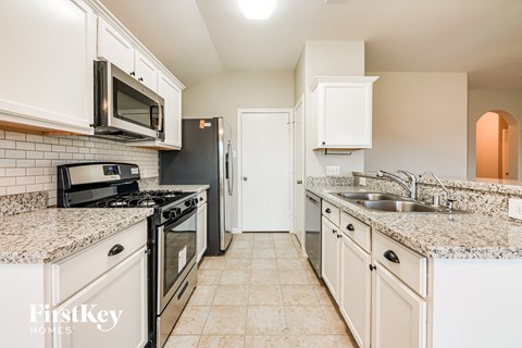 A kitchen with granite countertops and white cabinets.