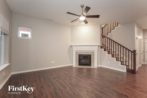 A spacious living room with a fireplace and a staircase.