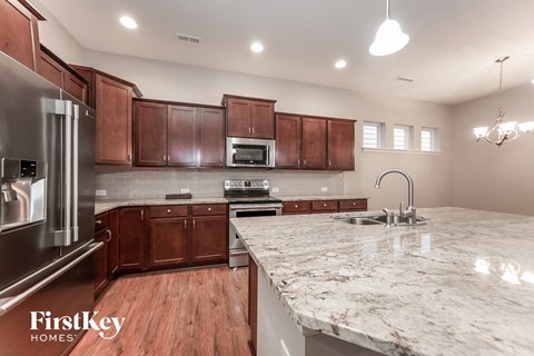 A kitchen with wooden cabinets and a marble countertop.