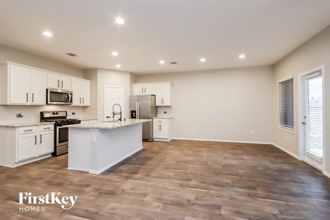 A kitchen with white cabinets and a wooden floor.