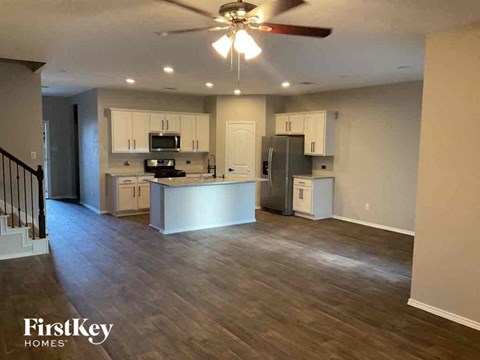 A spacious kitchen with a fan and wooden flooring.