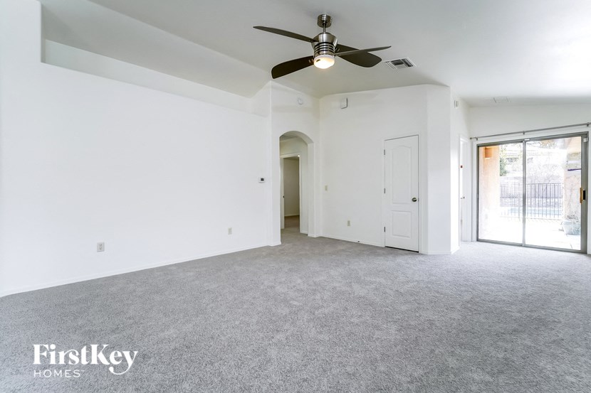 an empty living room with a ceiling fan and white walls