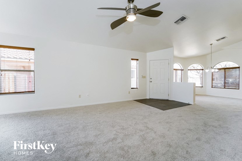an empty living room with a ceiling fan