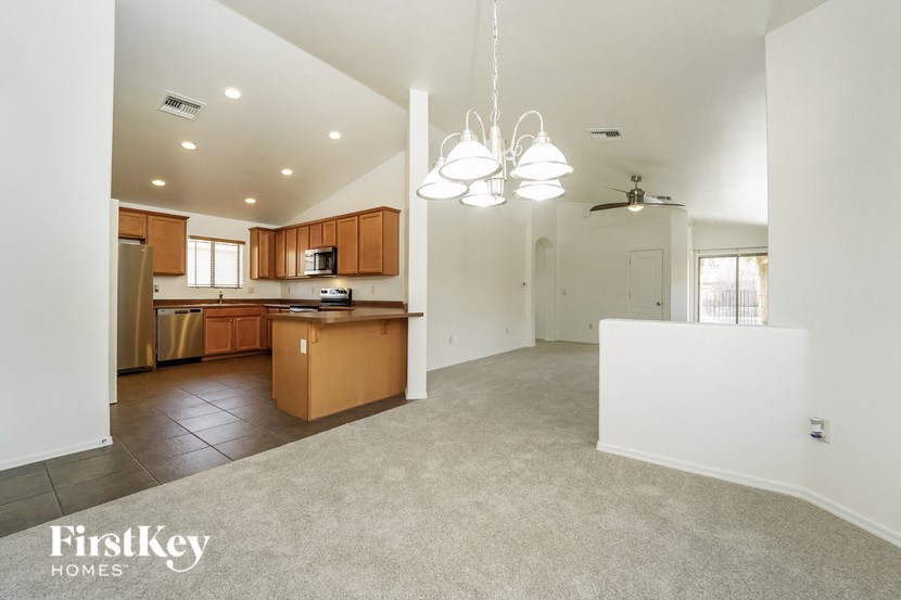 an empty kitchen and living room with a kitchen counter top and a refrigerator