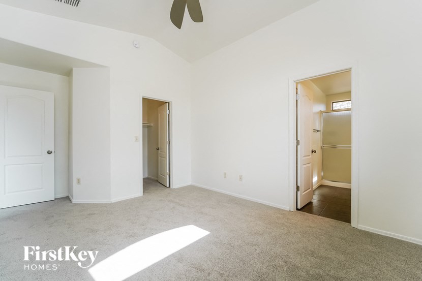 an empty living room with white walls and a ceiling fan