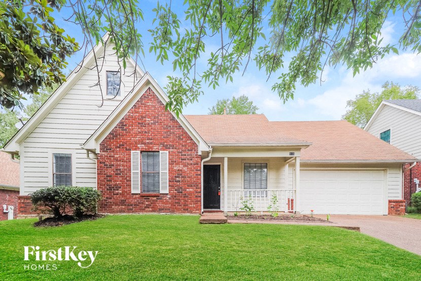 a white house with a lawn and a tree