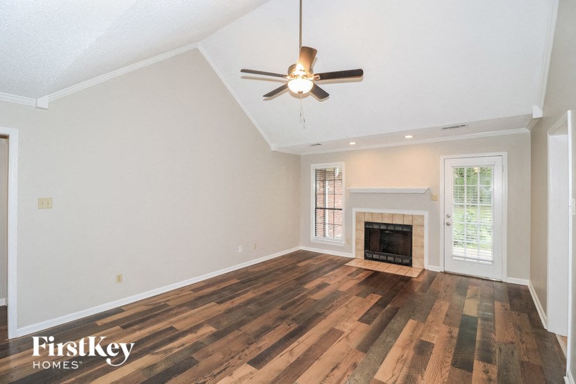 the living room with a fireplace and a ceiling fan