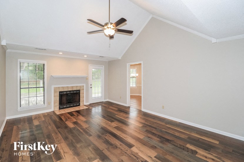 an empty living room with a ceiling fan and a fireplace